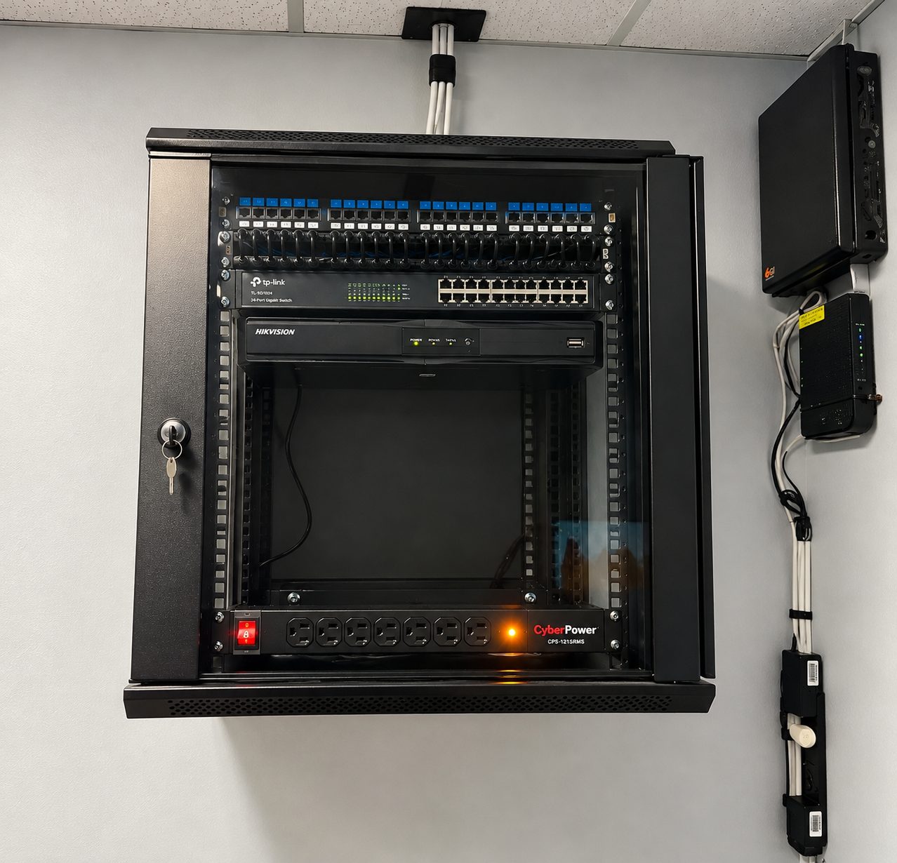 ISEEU TECHS installation: clean wall-mounted network rack with labeled patch panel, switch and recorder