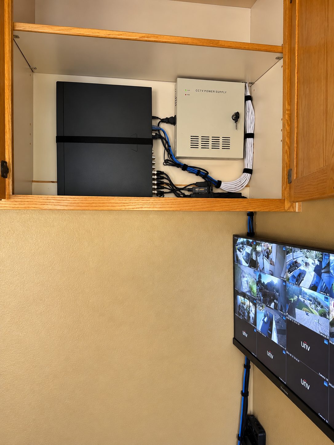 ISEEU TECHS installation: organized CCTV recorder and power supply cabinet with a live camera monitor