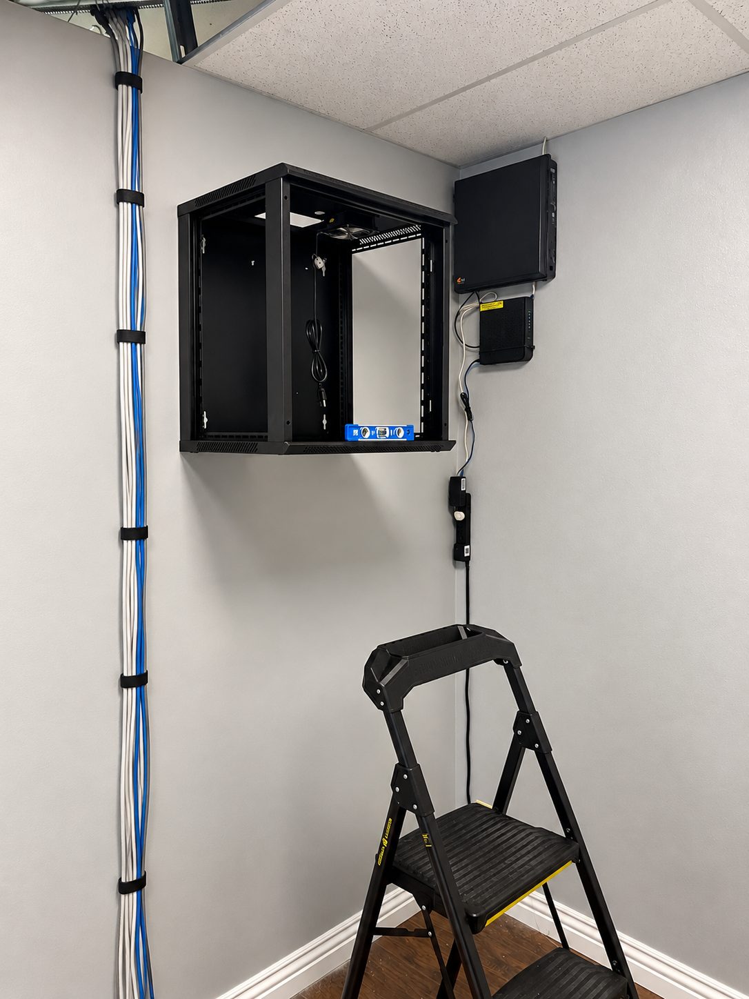 ISEEU TECHS installation: tidy office network rack with dressed cabling and a step ladder on site